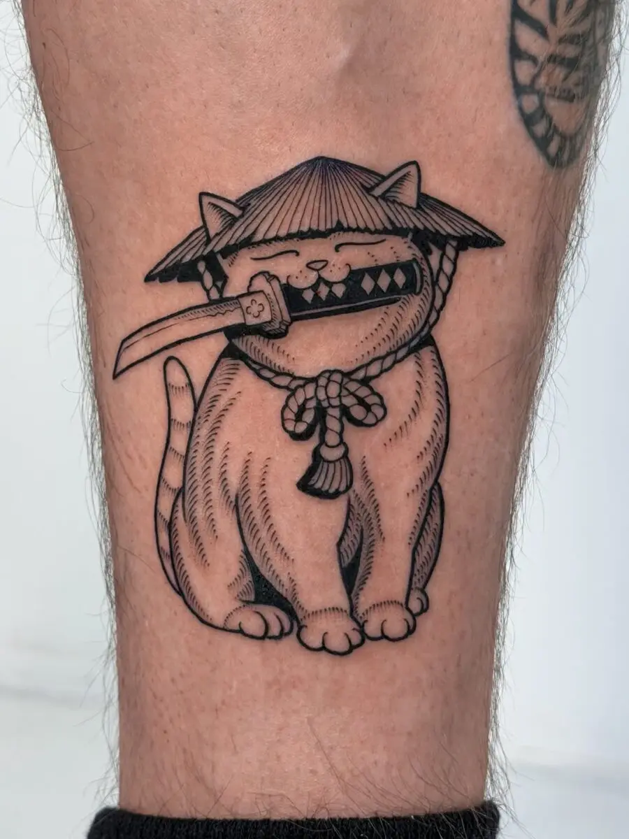A comical feline in samurai attire tattoo
