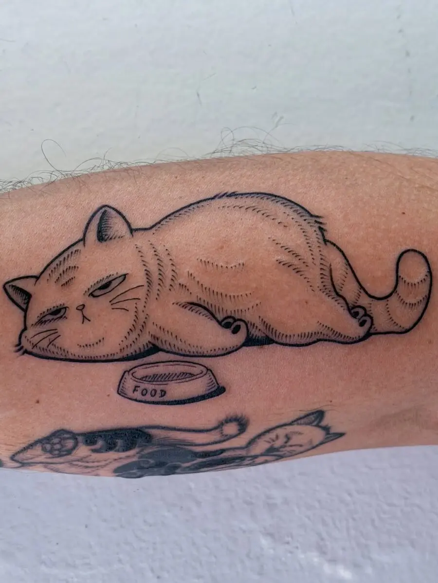 Charming cat lounging by food bowl tattoo