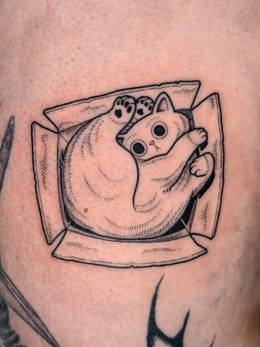 A quirky cat tattoo in a cardboard box