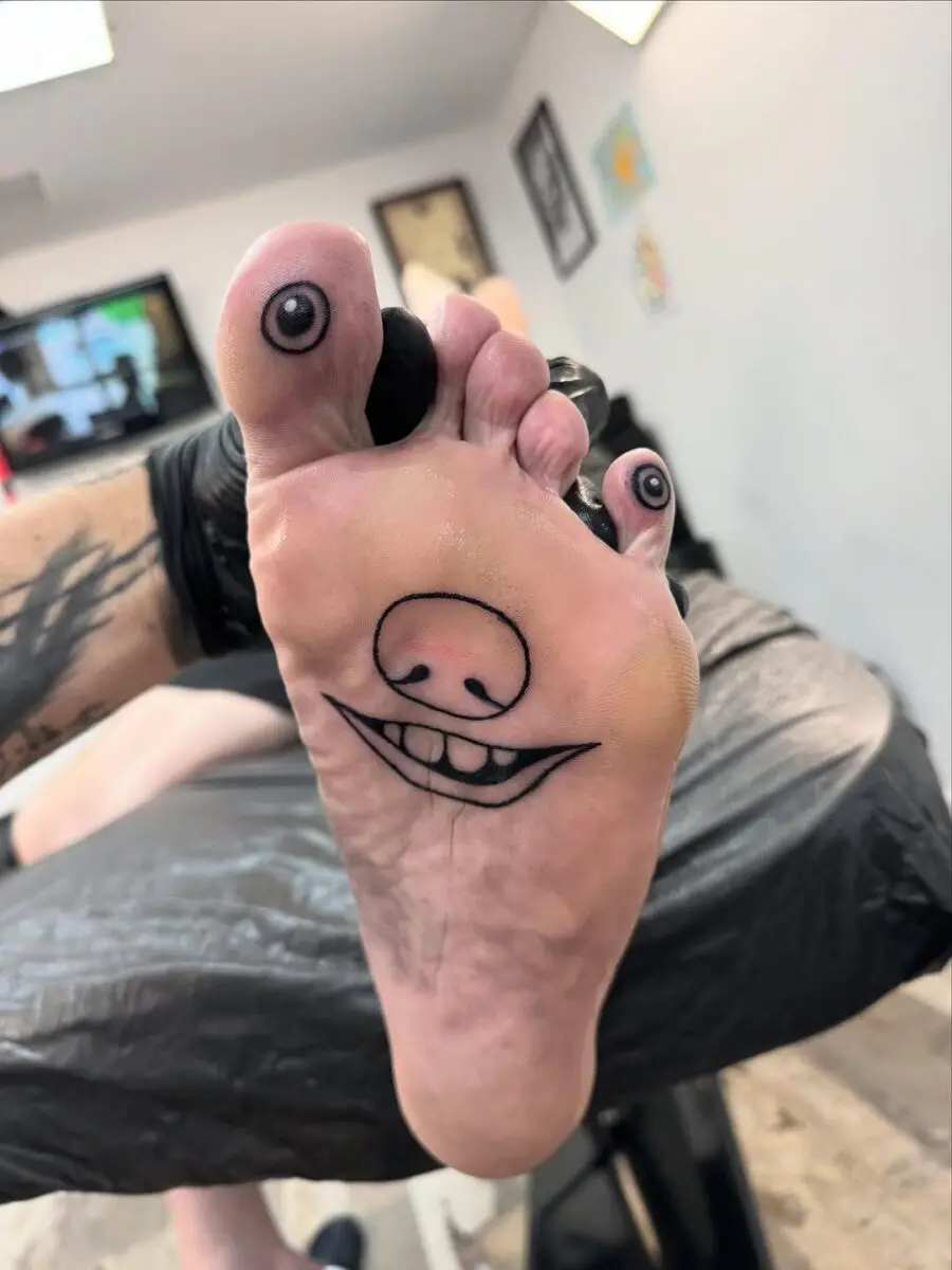 Whimsical foot tattoo with a cheeky grin