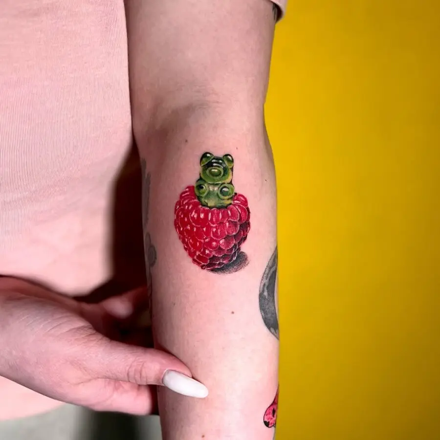 Whimsical gummy bear atop a berry tattoo