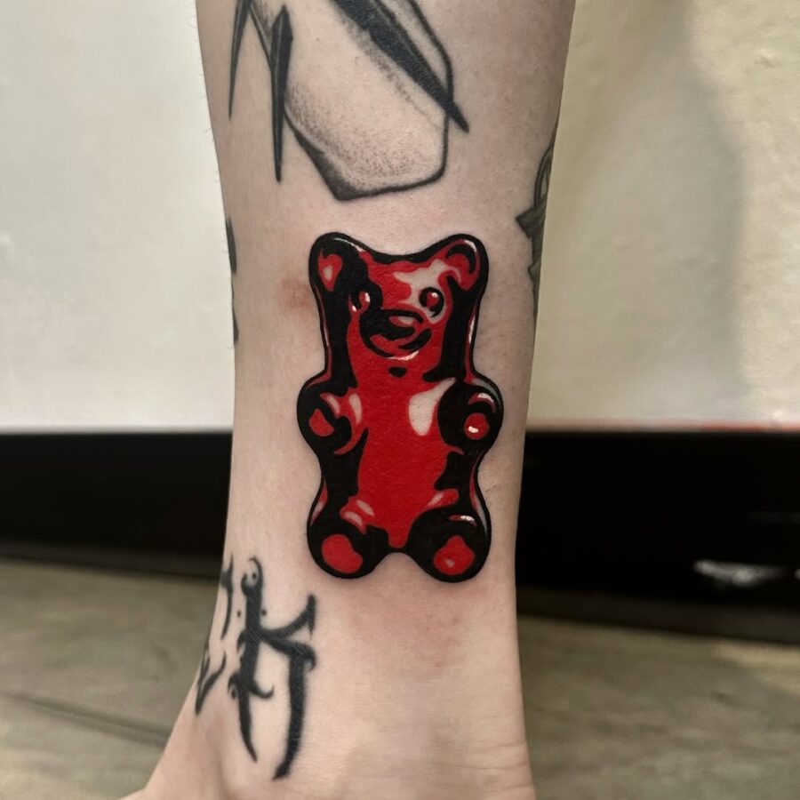 Vibrant red gummy bear tattoo on ankle