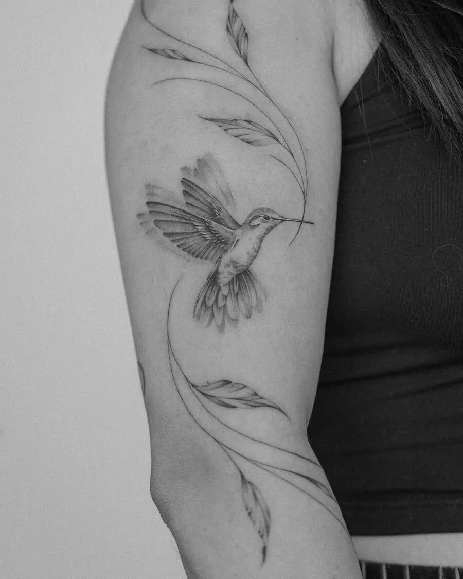 A delicate hummingbird tattoo with flowing leaves