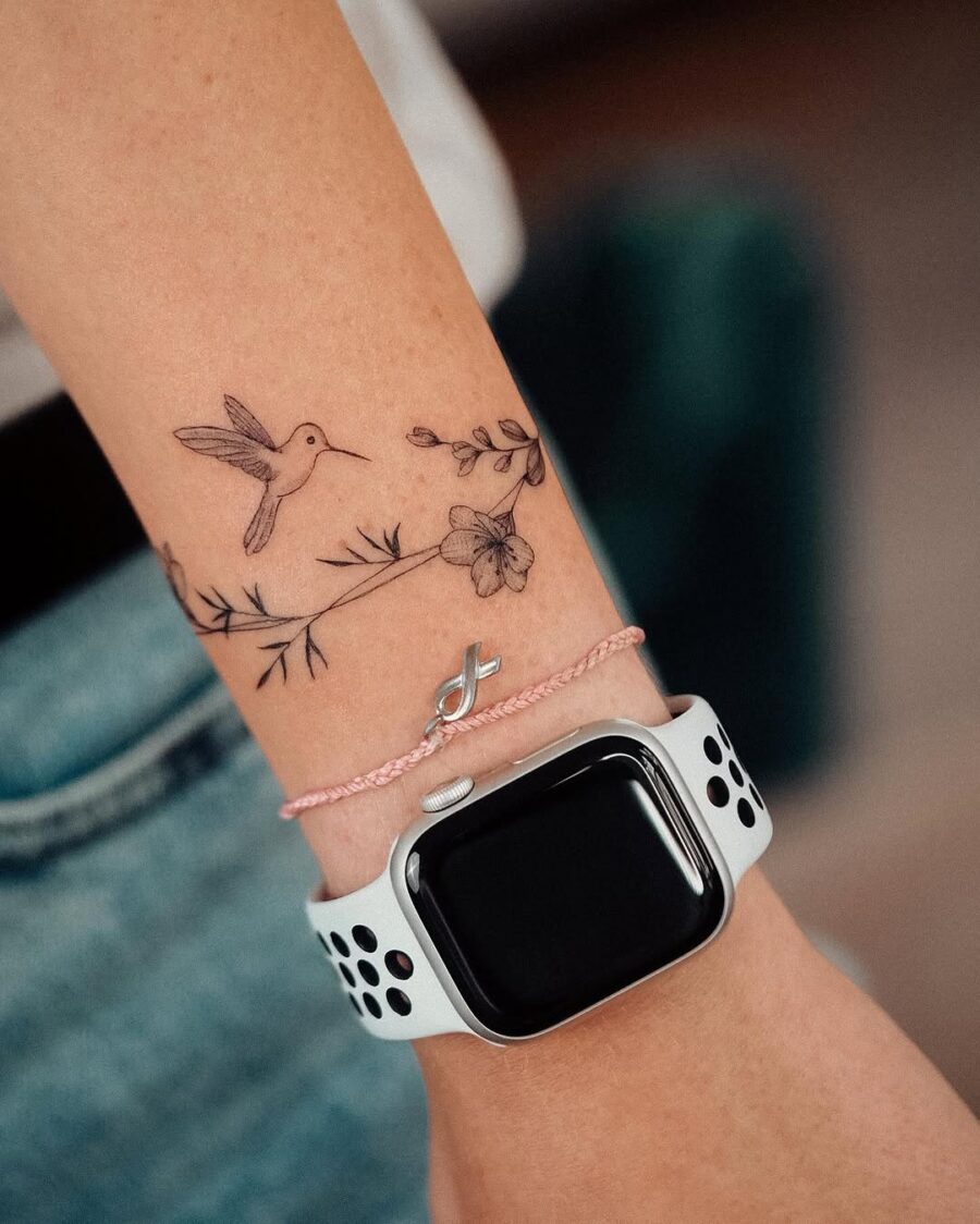 Delicate hummingbird tattoo adorned with flowers