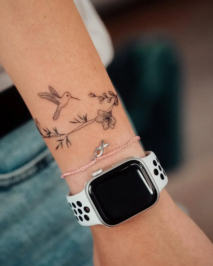 Delicate hummingbird tattoo adorned with flowers