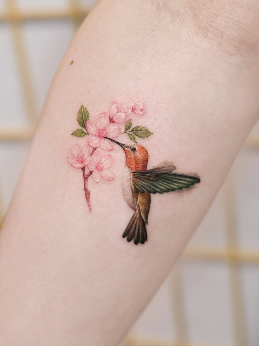 Graceful hummingbird tattoo amongst delicate blossoms