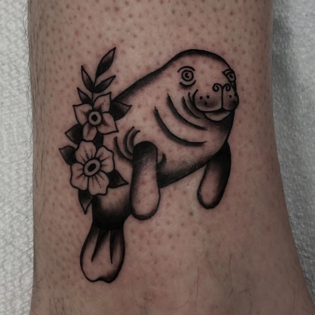 Whimsical manatee tattoo with floral elements