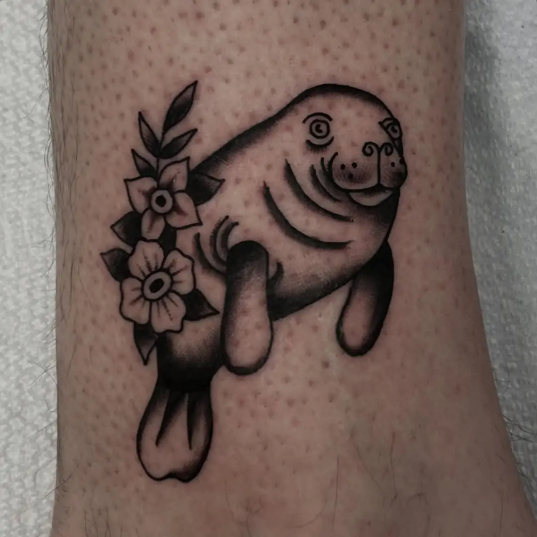 Whimsical manatee tattoo with floral elements