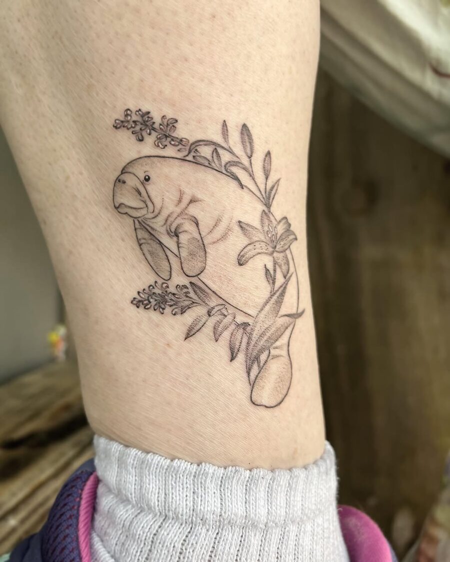 Elegant manatee tattoo surrounded by floral elements.