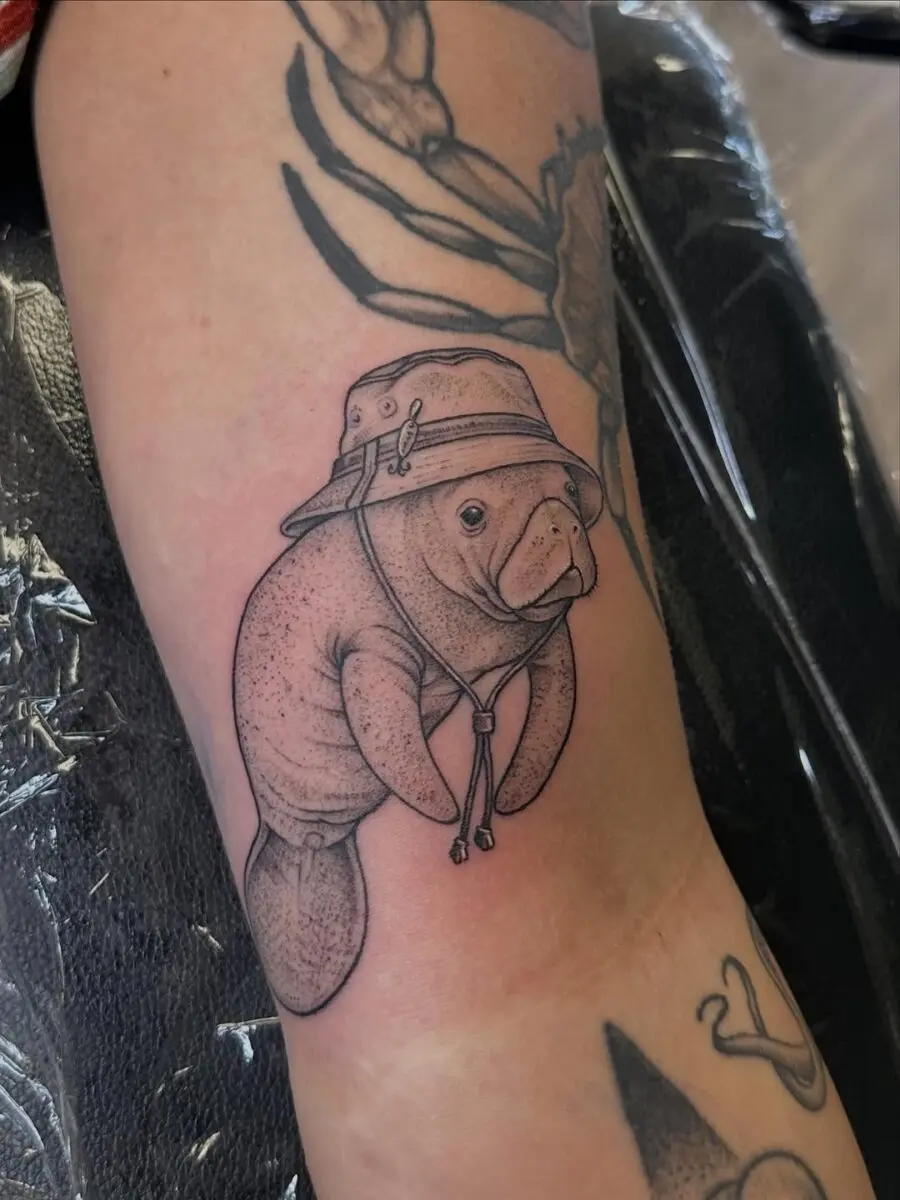 Playful Manatee Tattoo in a Stylish Hat