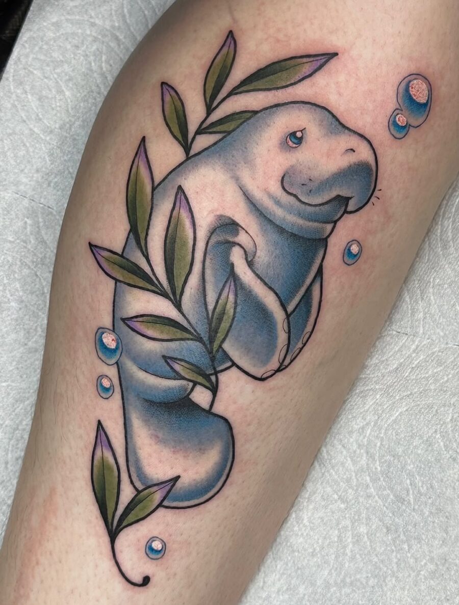 Charming manatee tattoo with leafy accents