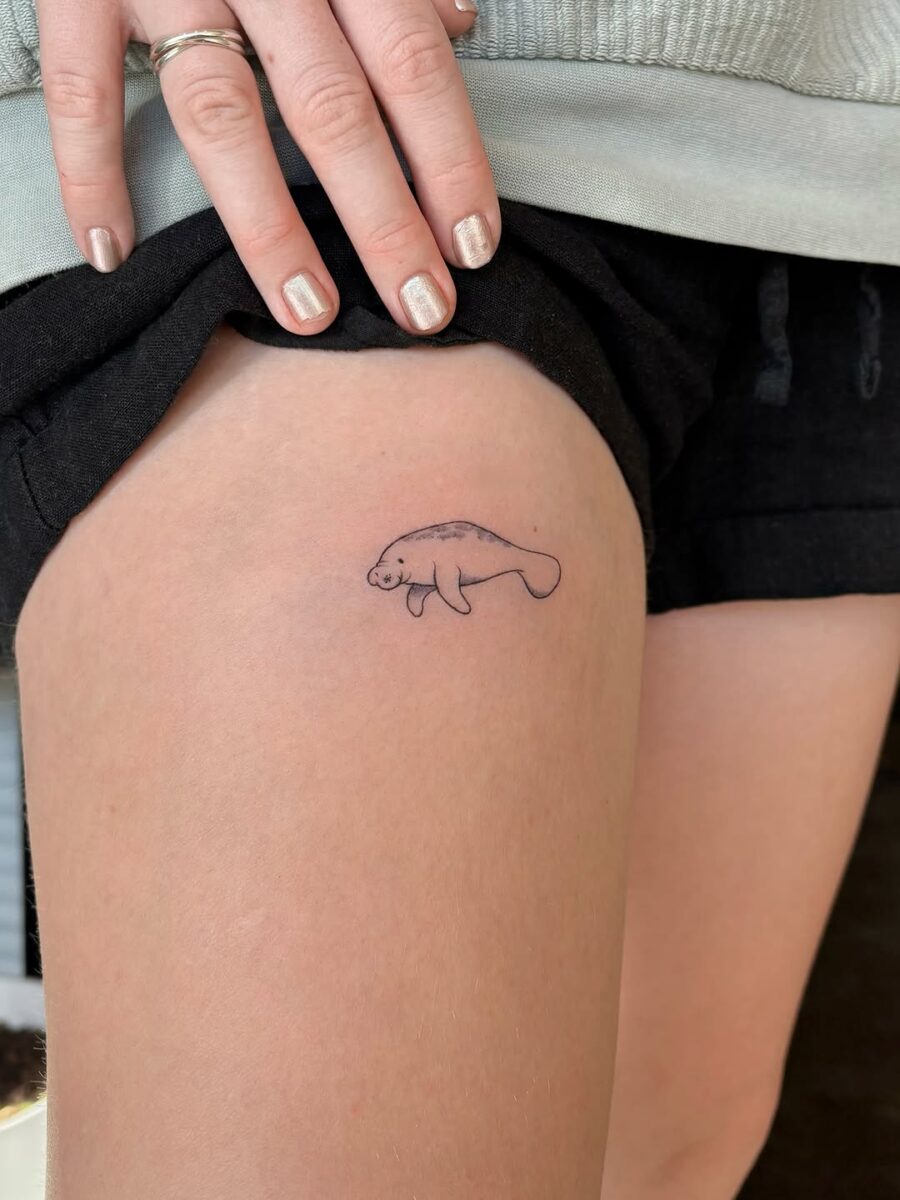 Cute minimalistic manatee tattoo on thigh