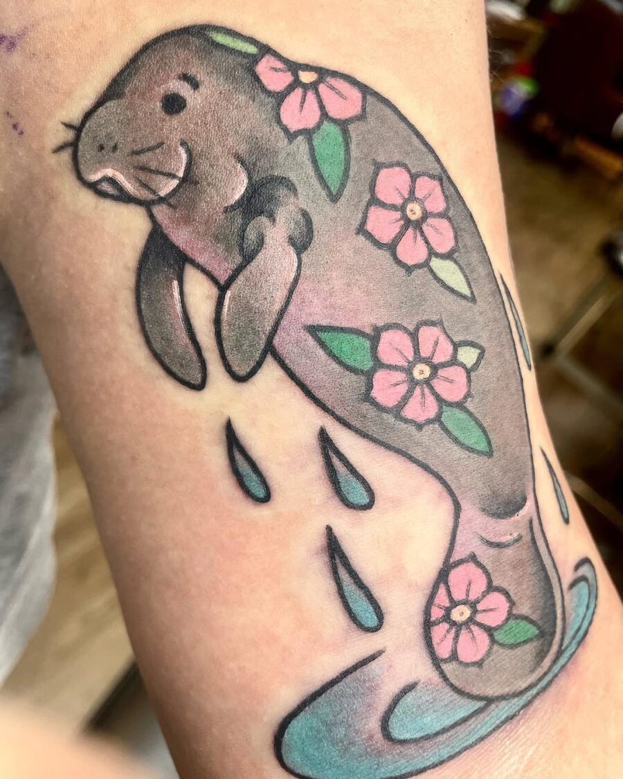 Charming manatee tattoo with floral accents