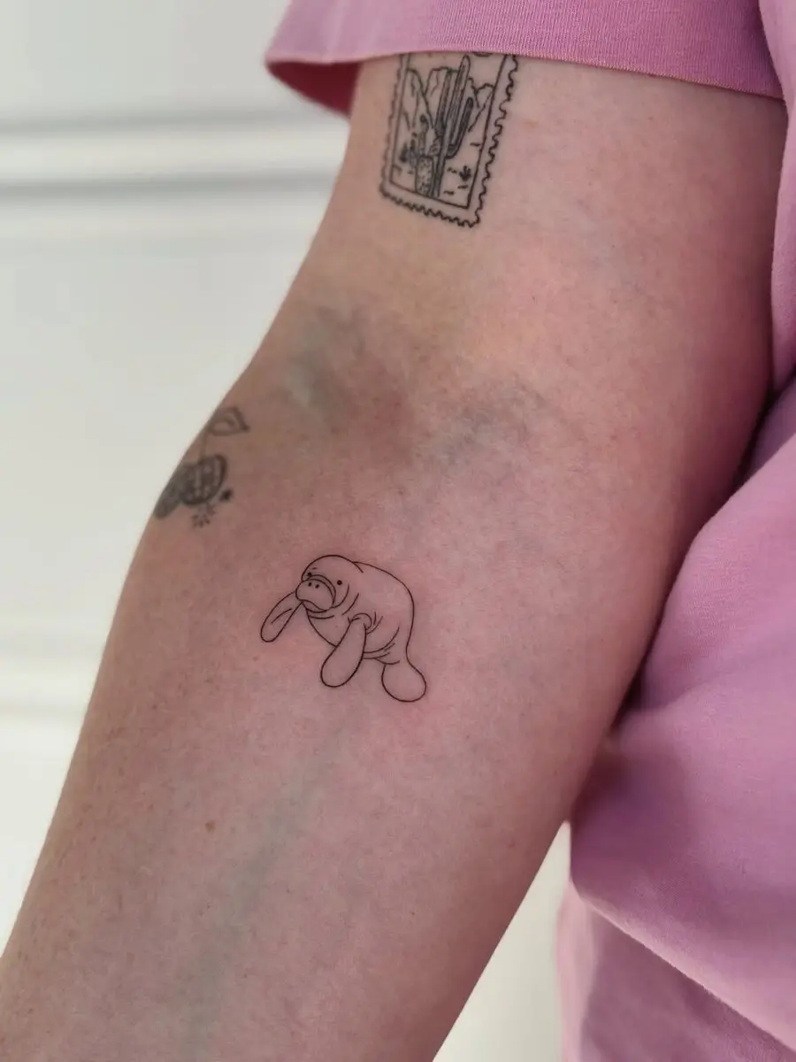 Charming minimalist manatee tattoo on arm