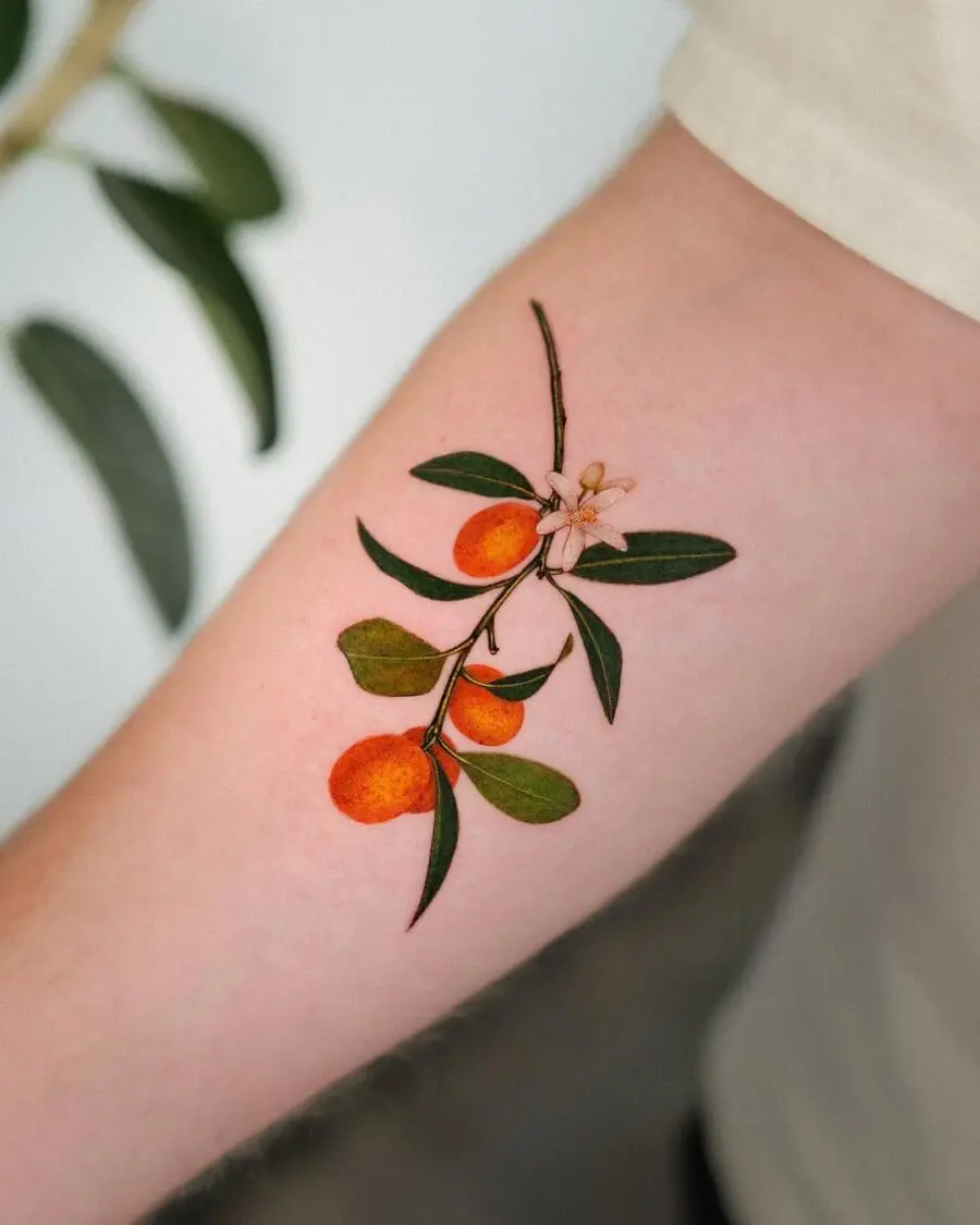 Elegant orange branch tattoo on the forearm