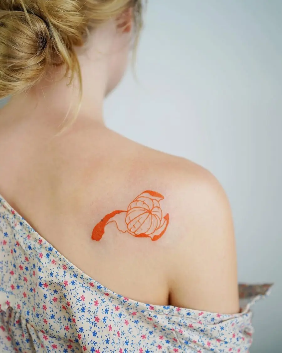 Delicate orange floral tattoo on shoulder
