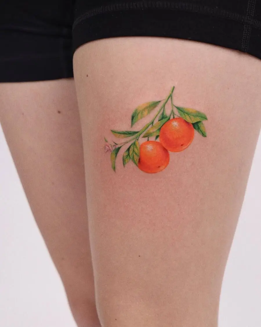 Vibrant orange tattoo with lush green leaves