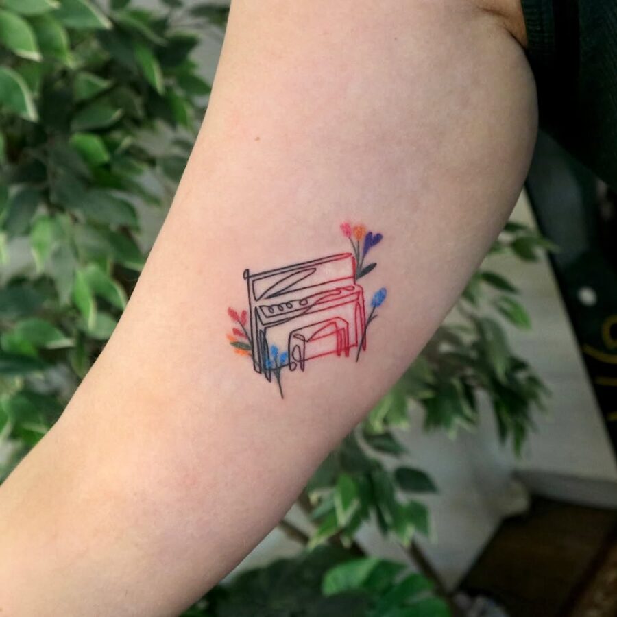 A vibrant piano tattoo surrounded by flowers