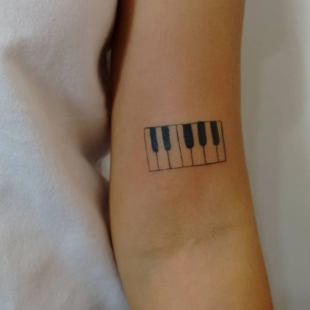 Minimalist piano tattoo on forearm