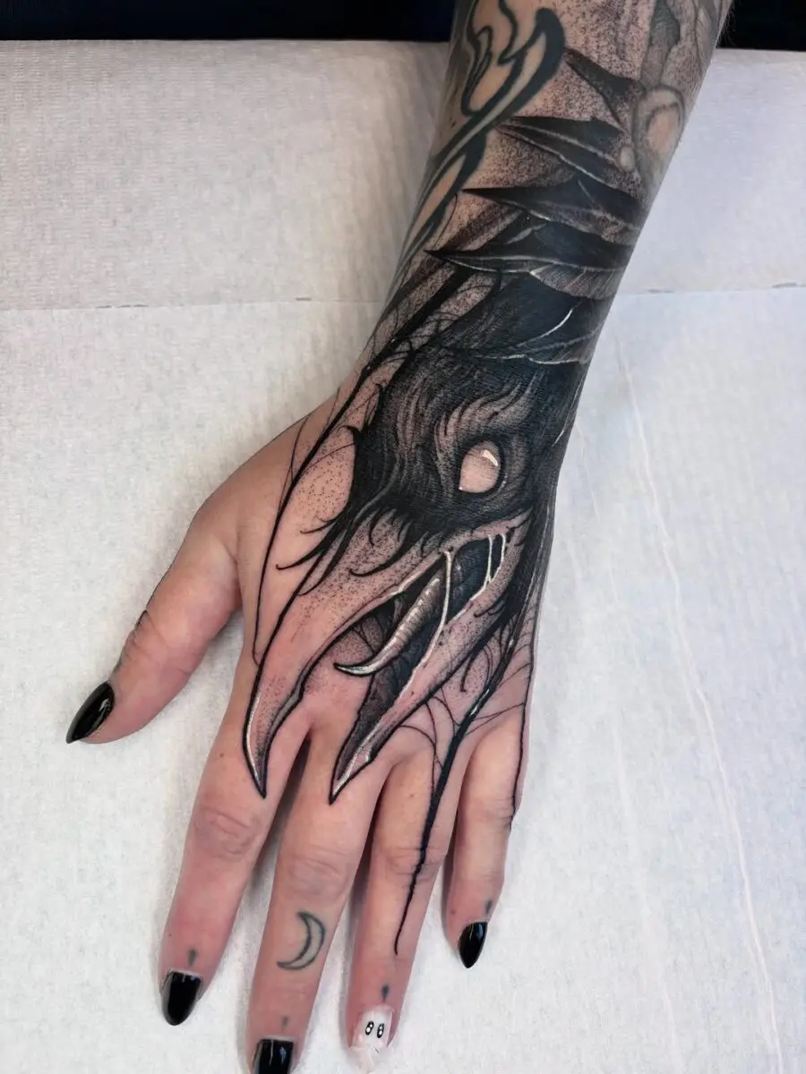 Intricate raven claw tattoo on the hand