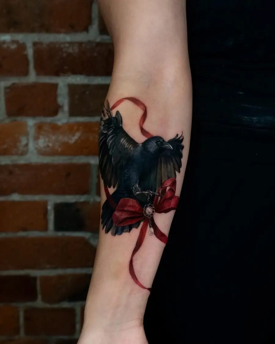 Elegant raven tattoo with striking red ribbon