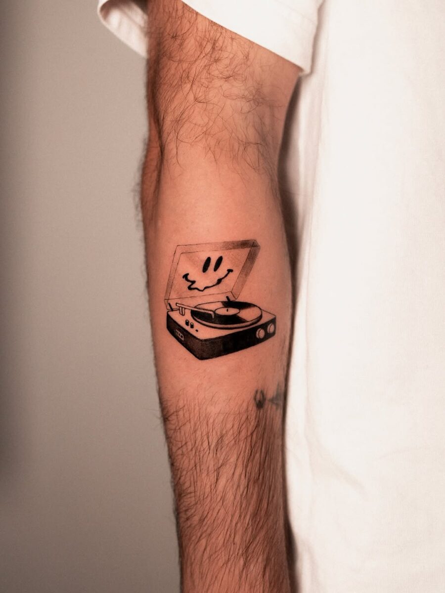 Playful record player tattoo with a smiley face