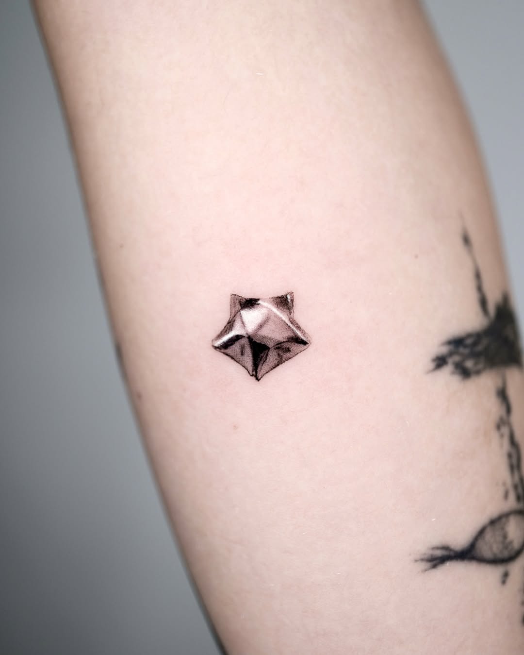 Stylish silver ink star tattoo on arm