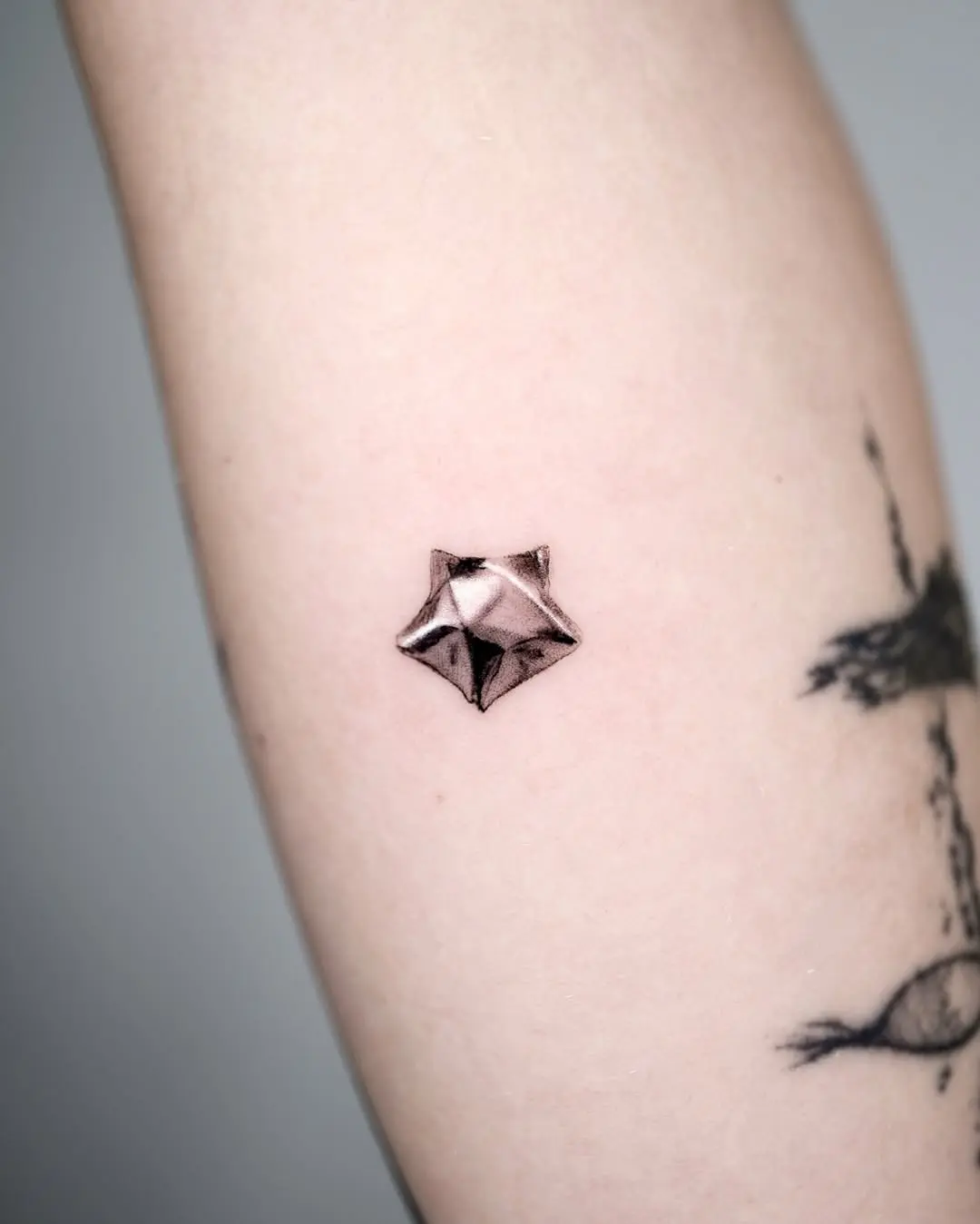 Stylish silver ink star tattoo on arm