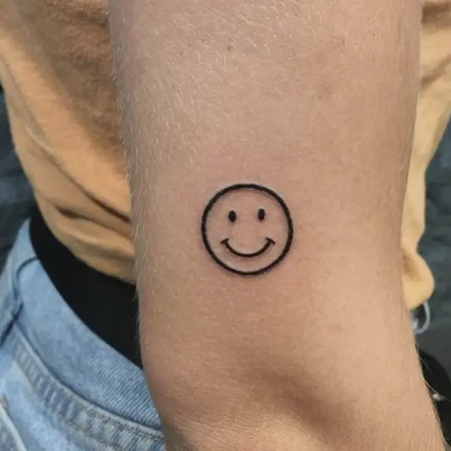 Minimalistic smiley face tattoo on forearm