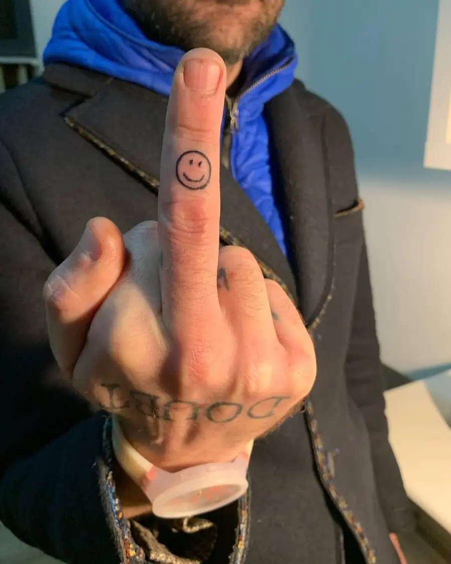 Unique smiley face tattoo on a finger