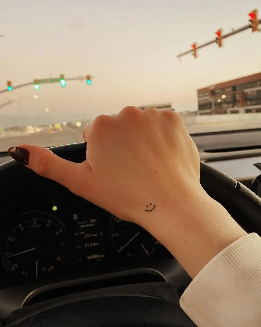 Charming smiley face tattoo on driving hand