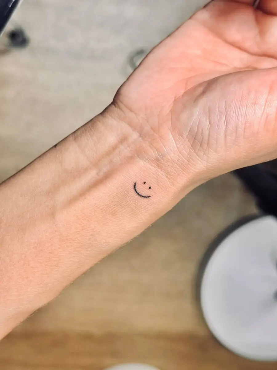 Minimalistic smiley face tattoo on wrist