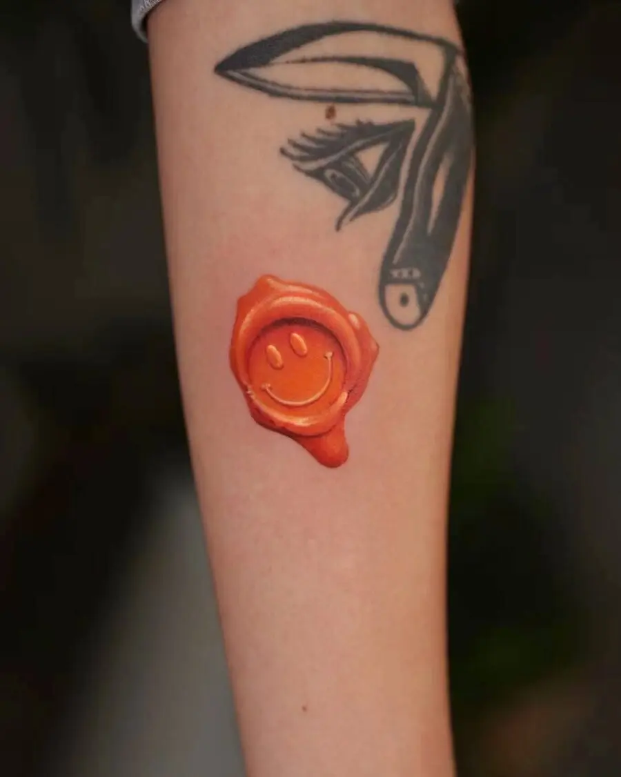 Vibrant Orange Smiley Face Tattoo on Arm
