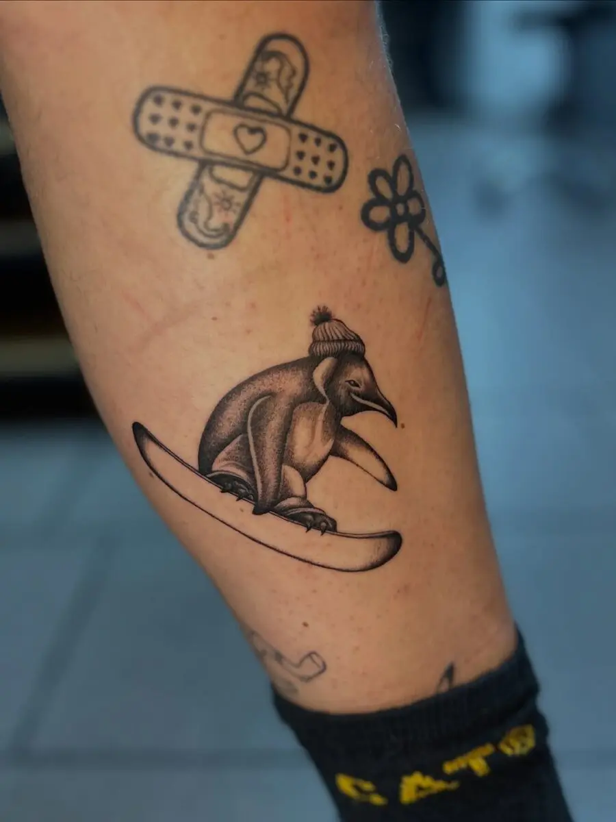 Whimsical penguin snowboard tattoo design