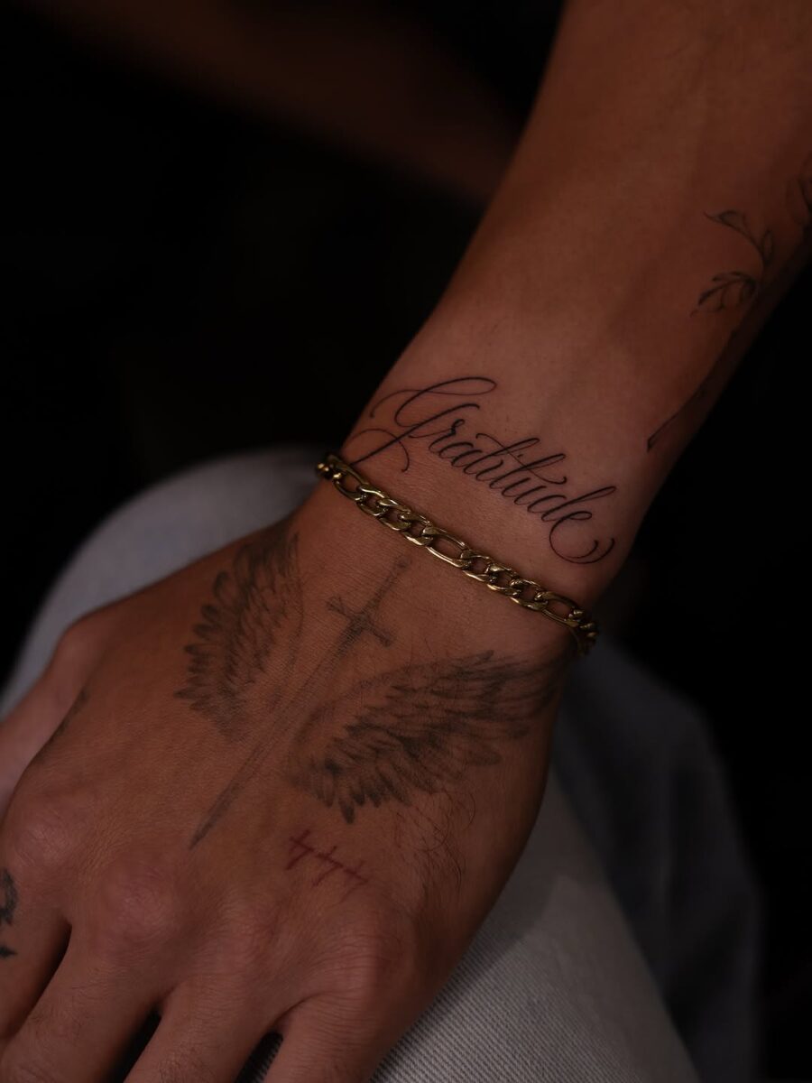 Elegant script tattoo with angel wings