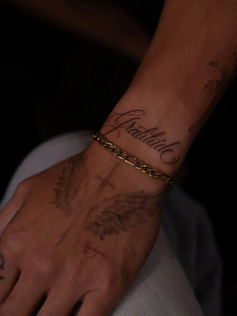 Elegant script tattoo with angel wings