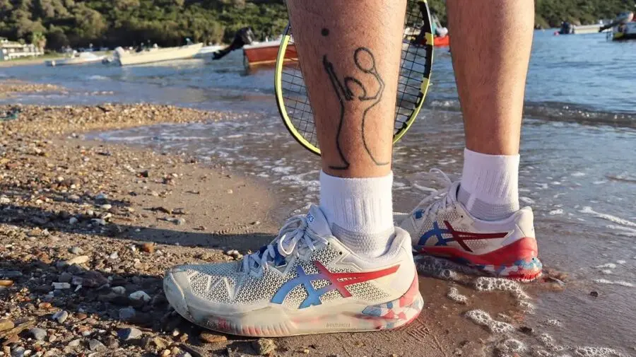 Playful tattoo celebrating tennis on the beach.