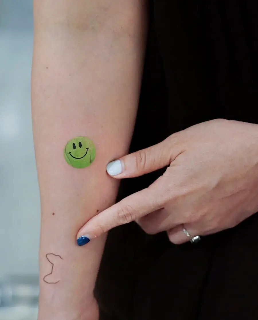 Playful smiley face tennis tattoo design