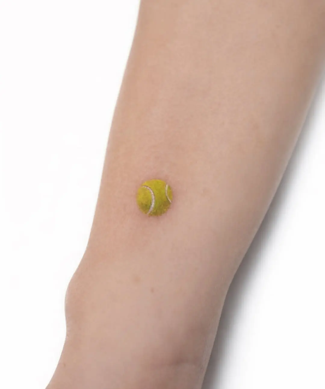 Minimalist tennis ball tattoo on the arm