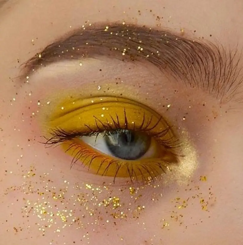 Vibrant yellow eye makeup with glitter accents