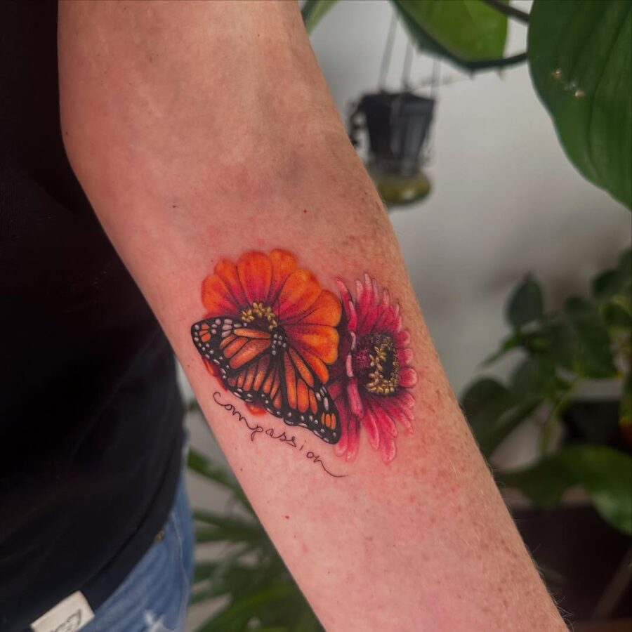 Vibrant zinnia tattoo with butterfly and text