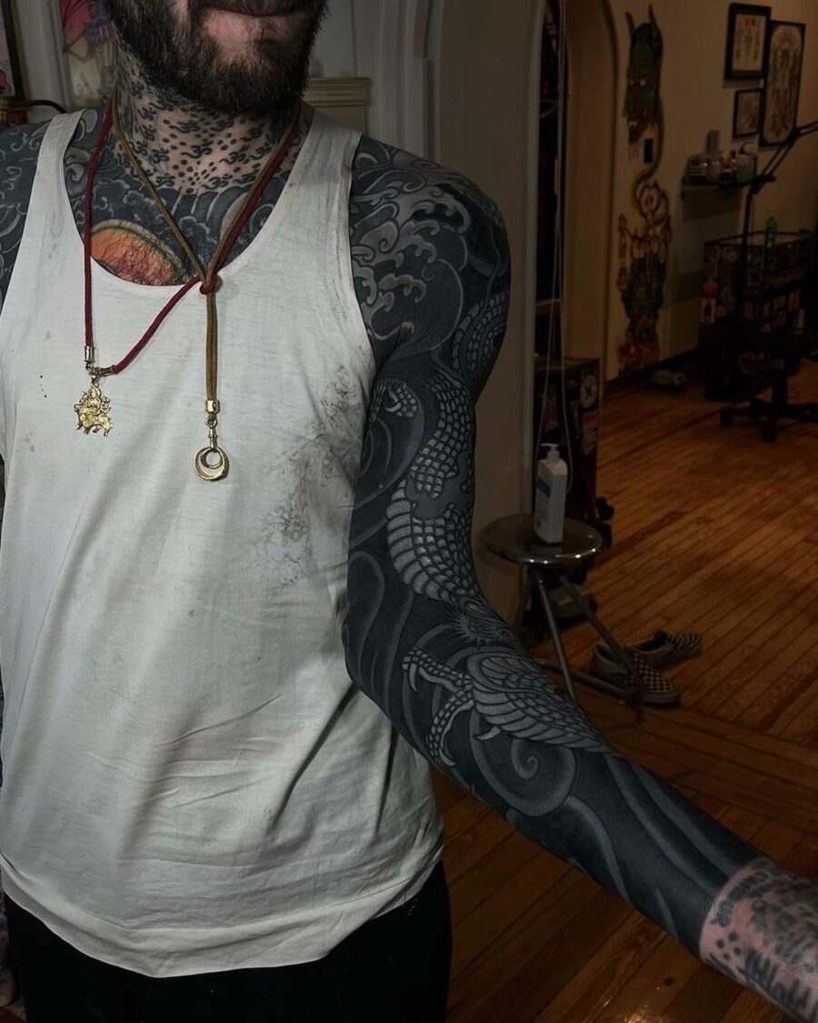 Intricate black sleeve tattoo showcasing a dragon