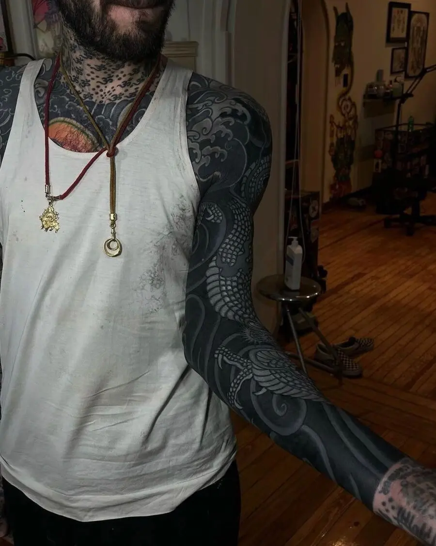 Intricate black sleeve tattoo showcasing a dragon