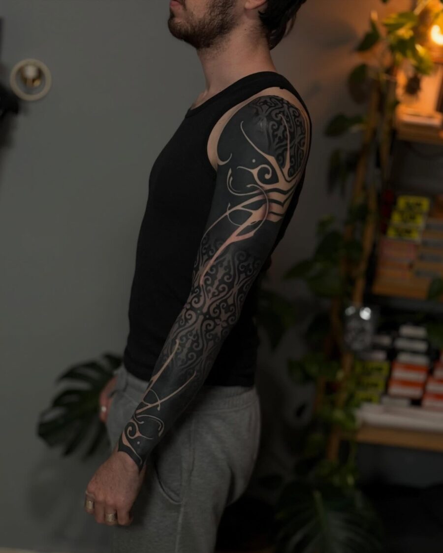 Intricate black sleeve tattoo on male arm