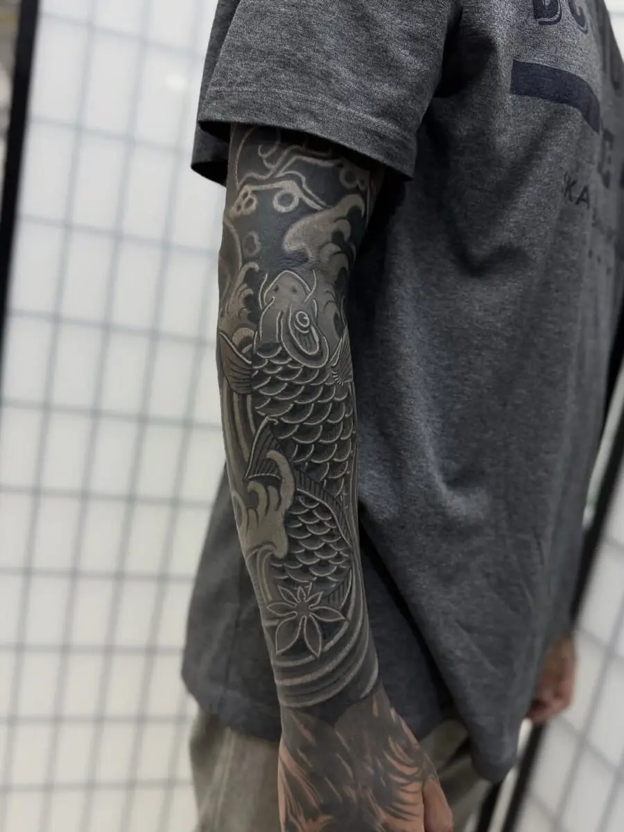 Sleek black sleeve tattoo of koi fish