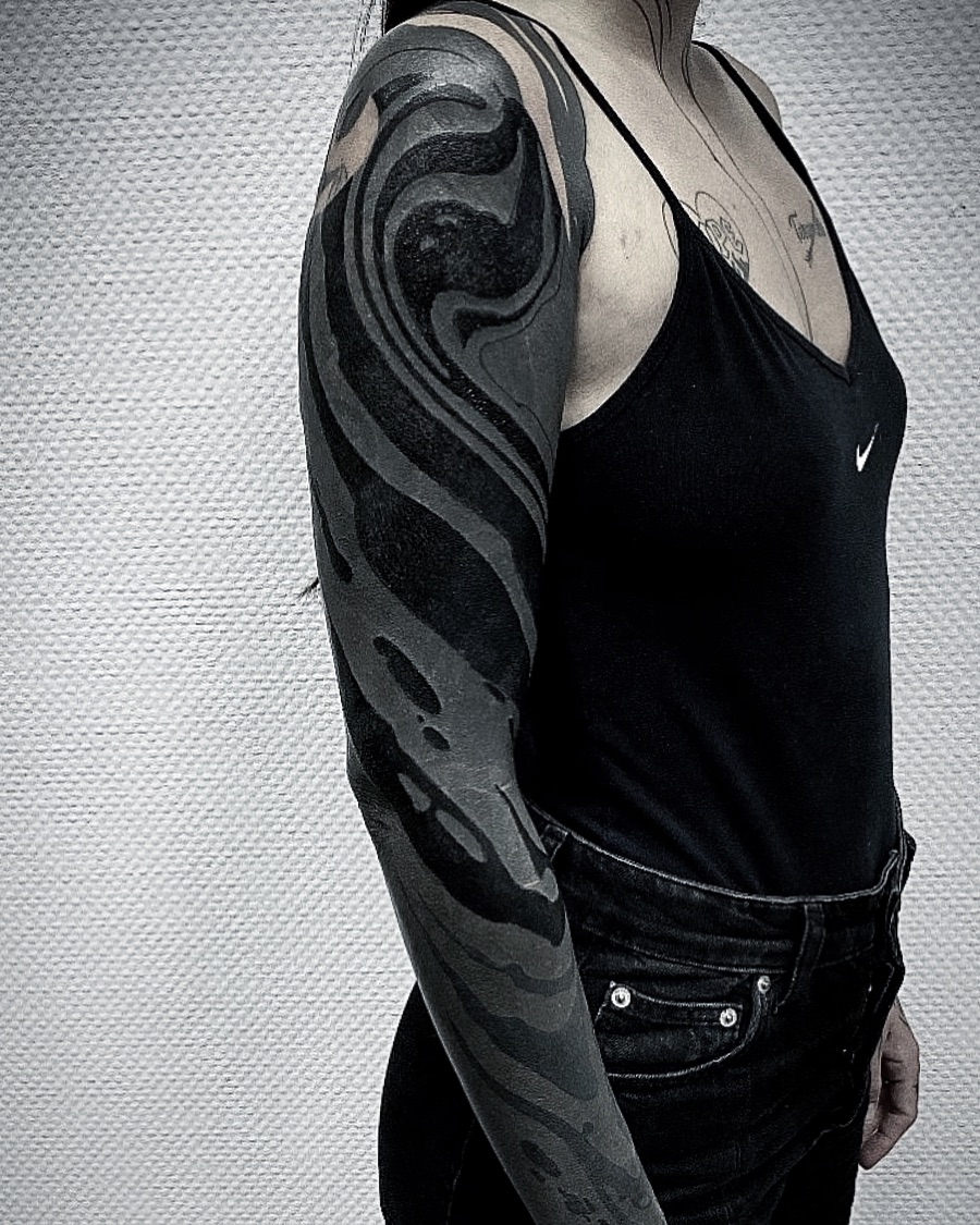 Striking black sleeve tattoo with fluid patterns