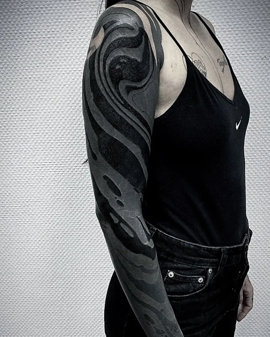 Striking black sleeve tattoo with fluid patterns