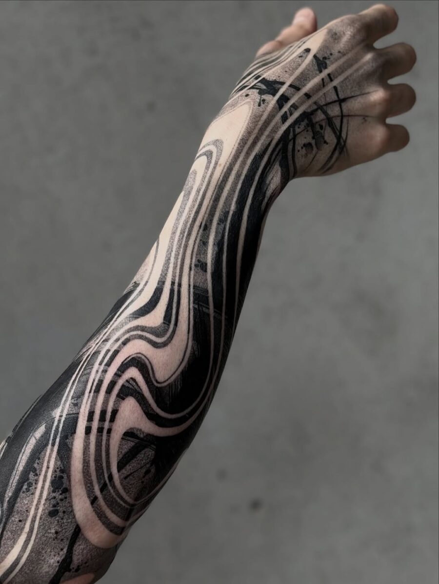 Intricate black wave patterns on sleeve tattoo