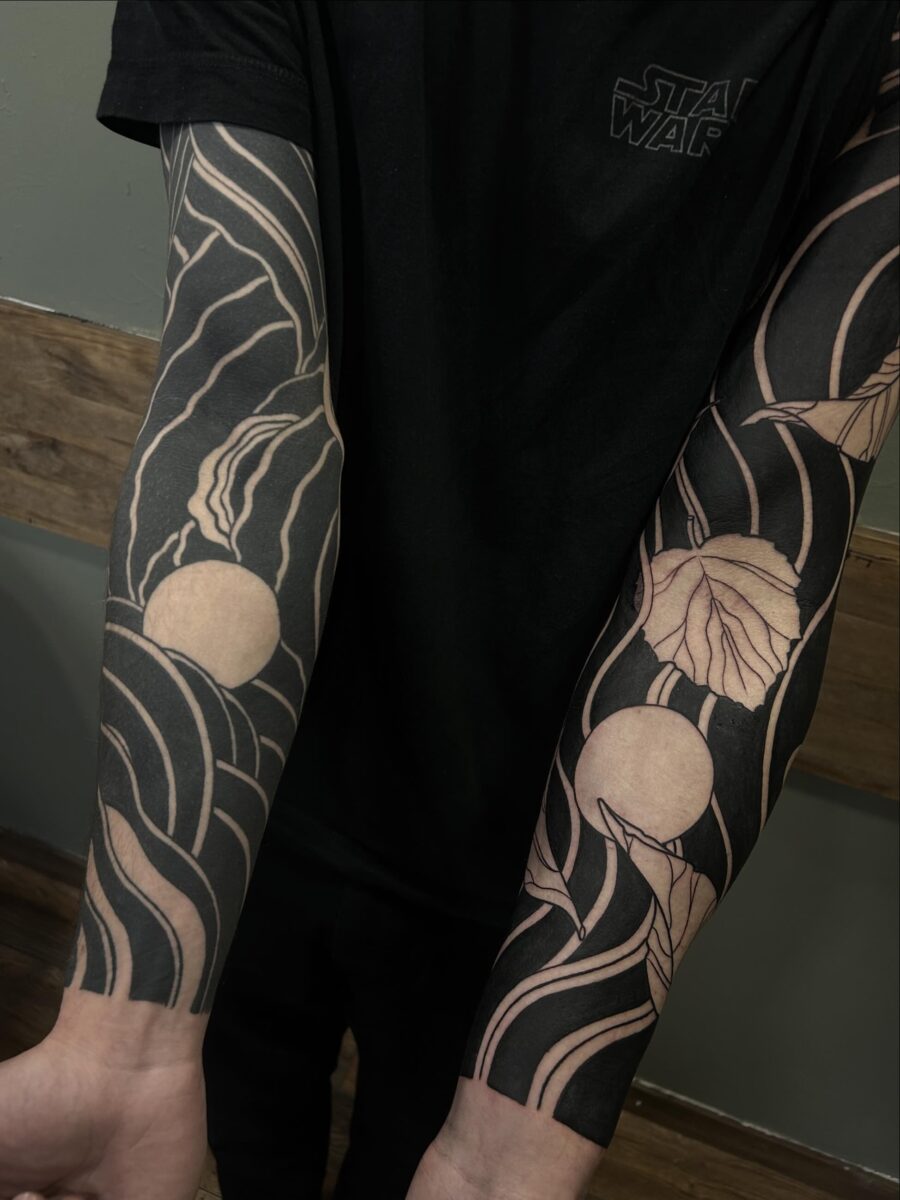 Artistic black sleeve tattoo with floral elements