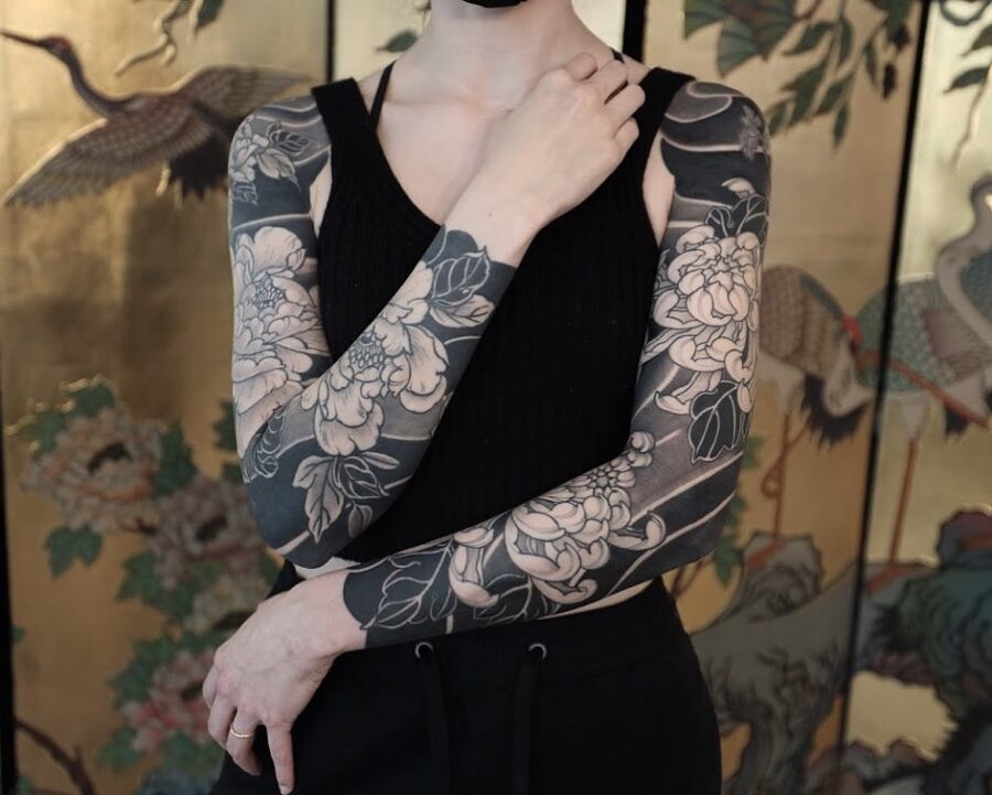 Elegant floral black sleeve tattoo design showcased
